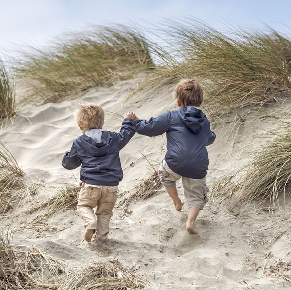 Zwei Kinder laufen am Strand entlang.